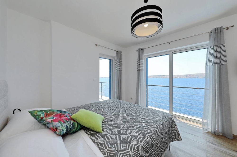 Sicht vom Doppelbett des Schlafzimmers mit großem Fenster und Sicht auf das Meer.