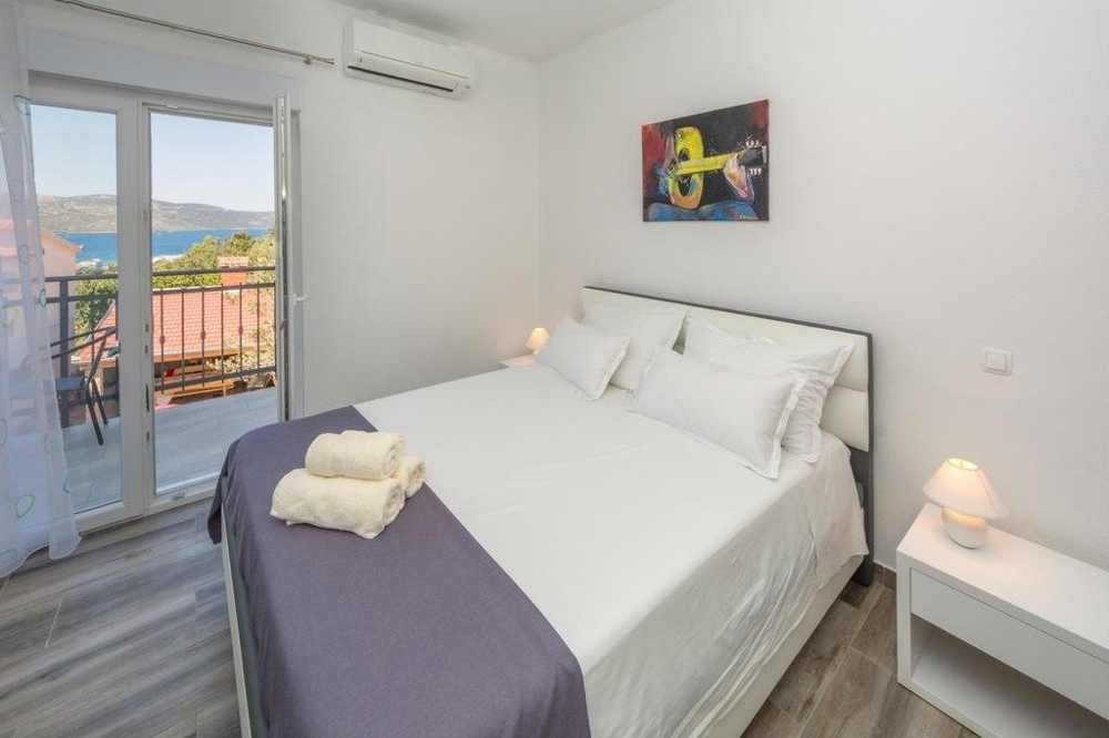 Ein Schlafzimmer mit einem Doppelbett und einem Balkon in Kroatien.