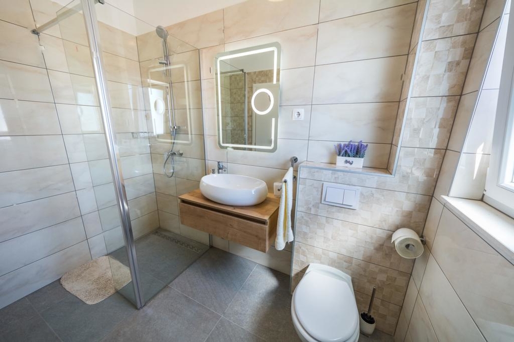 Ein Badezimmer mit ebenerdiger Dusche und WC der Immobilie H1467.