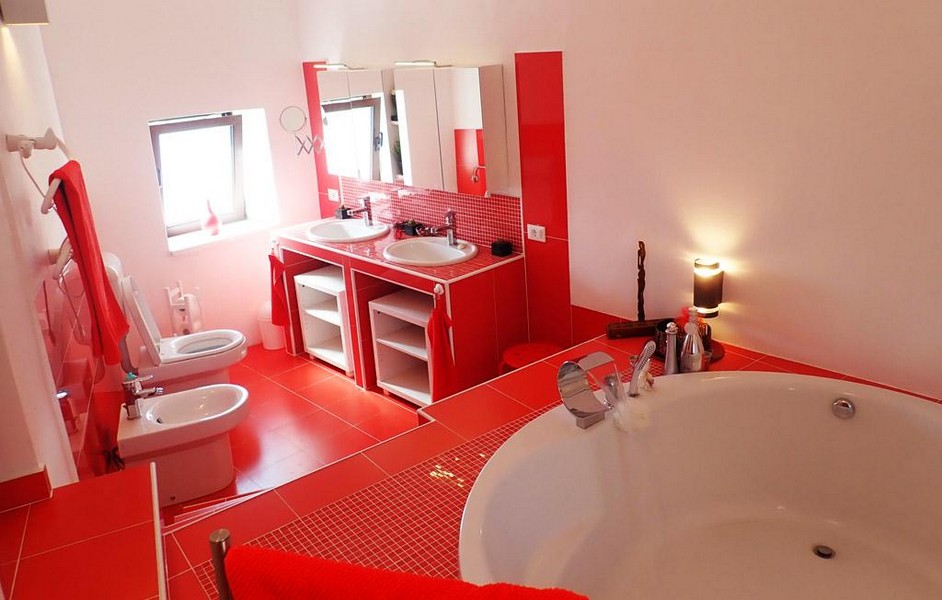 Ein modern eingerichtetes Badezimmer mit Badewanne, WC, Bidet und Fenster der Immobilie.
