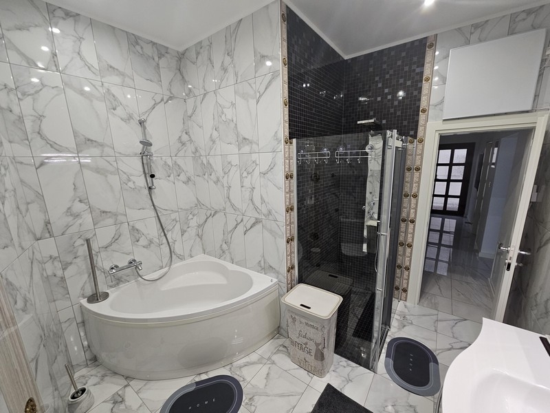 Elegantes Badezimmer mit Marmoroptik und Kombination aus Badewanne und Dusche in einer kroatischen Immobilie