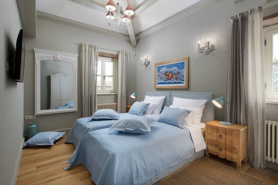 Komfortables Schlafzimmer in kroatischer Villa mit blauer Bettwäsche und Holzfußboden.