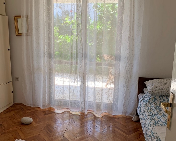 Helles Schlafzimmer mit Parkettboden und Fensterblick auf grüne Außenanlagen des Hauses in Peljesac