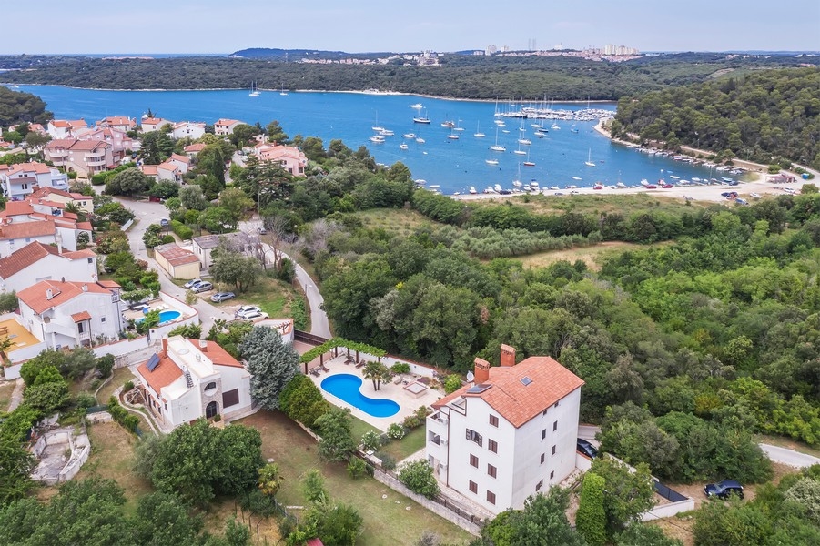 Immobilien Kroatien, Mehrfamilienhaus in Istrien mit Meerblick - Panorama Scouting H3025: Eine Luftaufnahme zeigt eine malerische Küstenstadt mit mehreren Häusern und Booten im Wasser