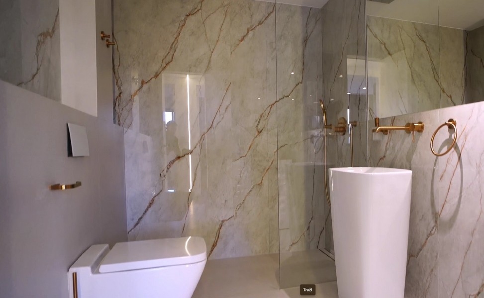 Exklusives Badezimmer mit marmorverkleideten Wänden in einer Wohnung am Meer in Kroatien, ausgestattet mit modernen Armaturen und einer freistehenden Badewanne.