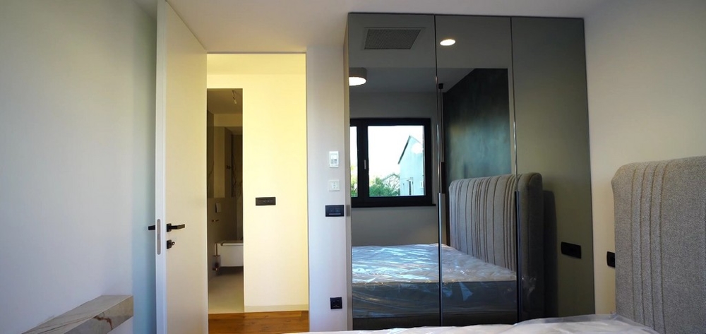 Schlafzimmer in einer Wohnung am Meer in Kroatien mit großen Fenstern und direktem Blick ins Badezimmer