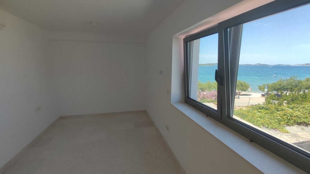 Penthouse kaufen Kroatien - Helles Penthouse mit geräumigem Zimmer und großen Fenstern, die einen malerischen Blick auf das Meer und die grüne Umgebung bieten, von Panorama Scouting.