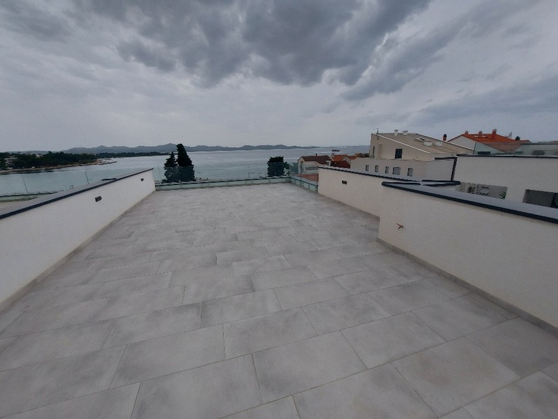 Leere Dachterrasse eines Penthouses zum Verkauf in Zadar, Kroatien, mit Meerblick und bewölktem Himmel