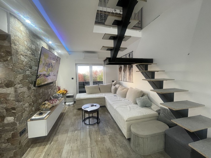 Wohnzimmer mit Ecksofa und offener Treppe